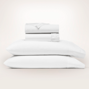 Boll & Branch Signature Hemmed Sheet Set in White, folded flat and fitted sheets stacked on two pillowcases