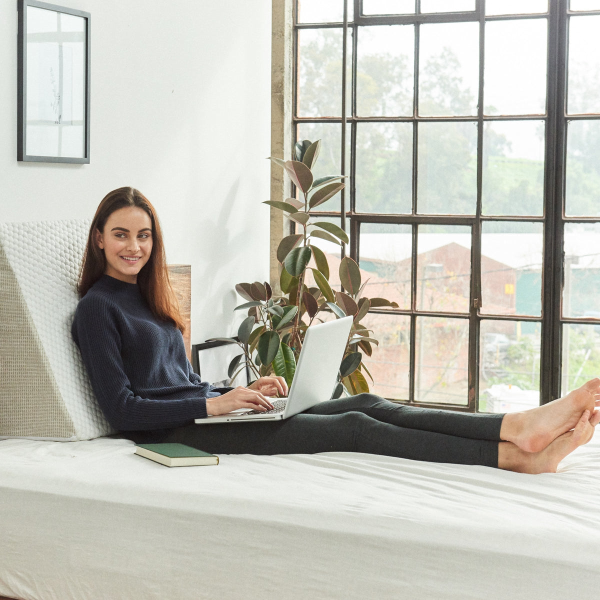 Sloped foam wedge pillow with removable stretch-knit cover resting on a bed — view 3