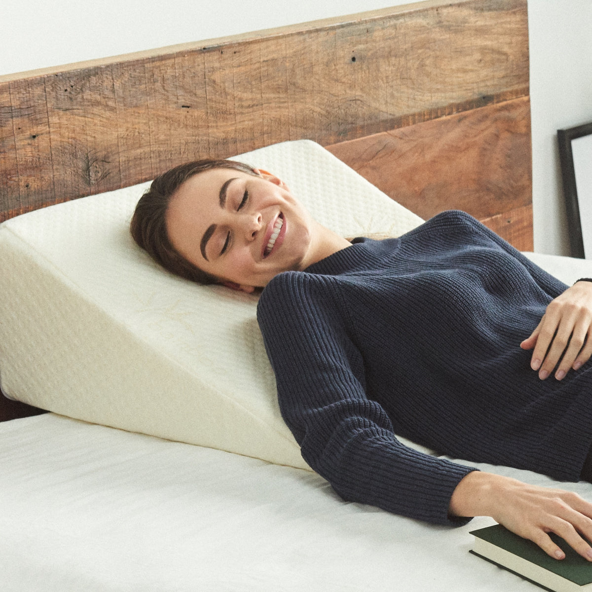 Sloped foam wedge pillow with removable stretch-knit cover resting on a bed — view 4