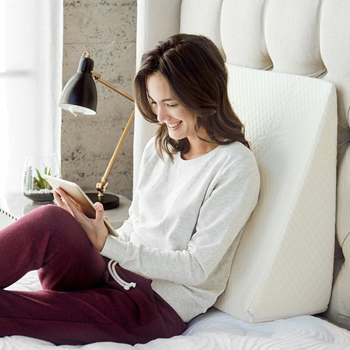 Sloped foam wedge pillow with removable stretch-knit cover resting on a bed — view 5