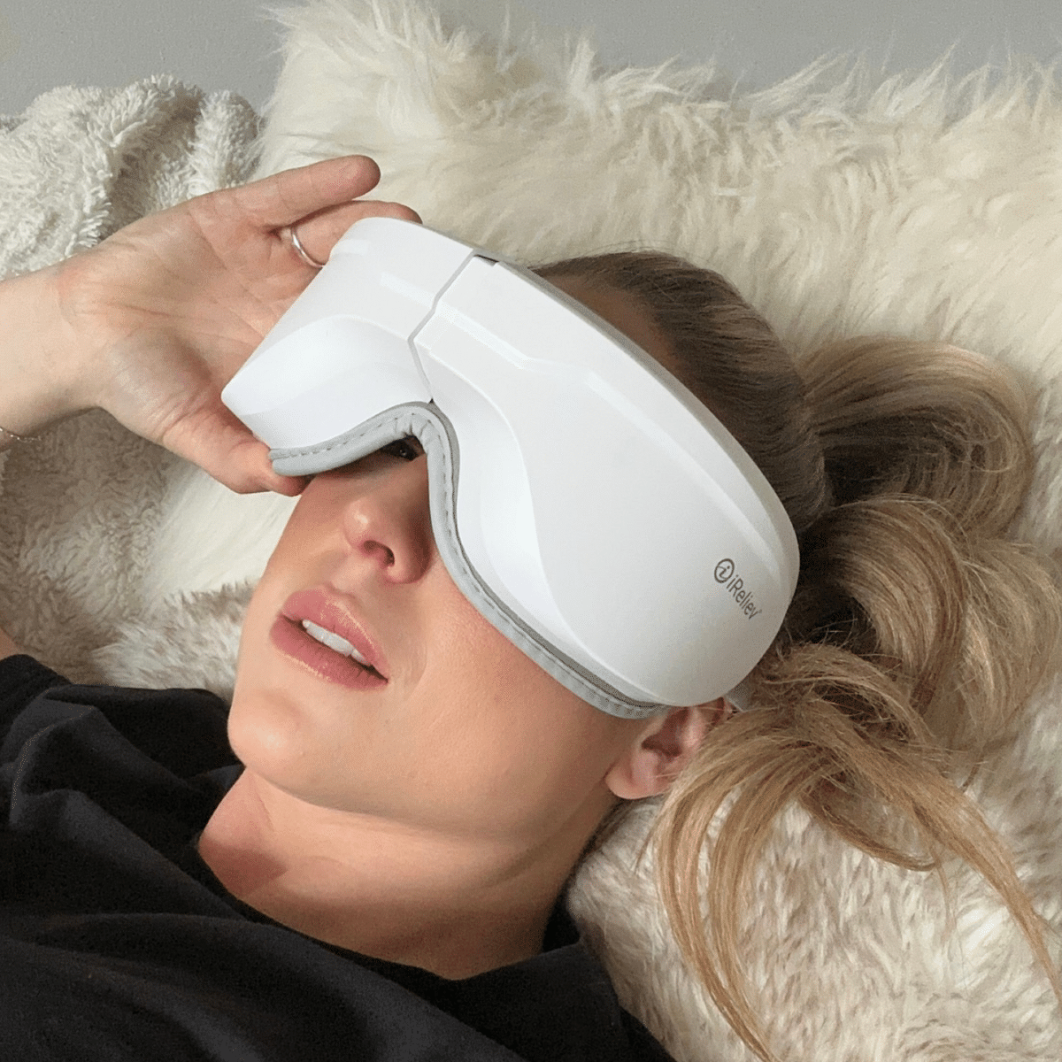 iReliev heated eye massager resting beside its matching neck pillow — view 3