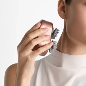 NeuroScent head and scalp massager held in one hand, a portable device for head, eye and sinus comfort