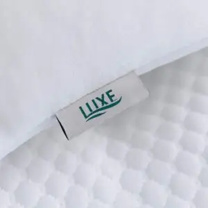 Luxe Mattresses memory foam neck pain pillow resting on a made bed
