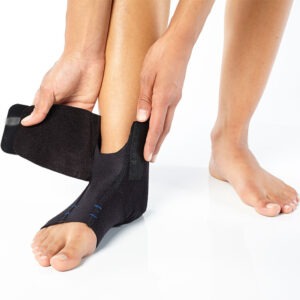 BioSkin black pull-on ankle support sleeve with stabilizing straps wrapped around a foot and ankle