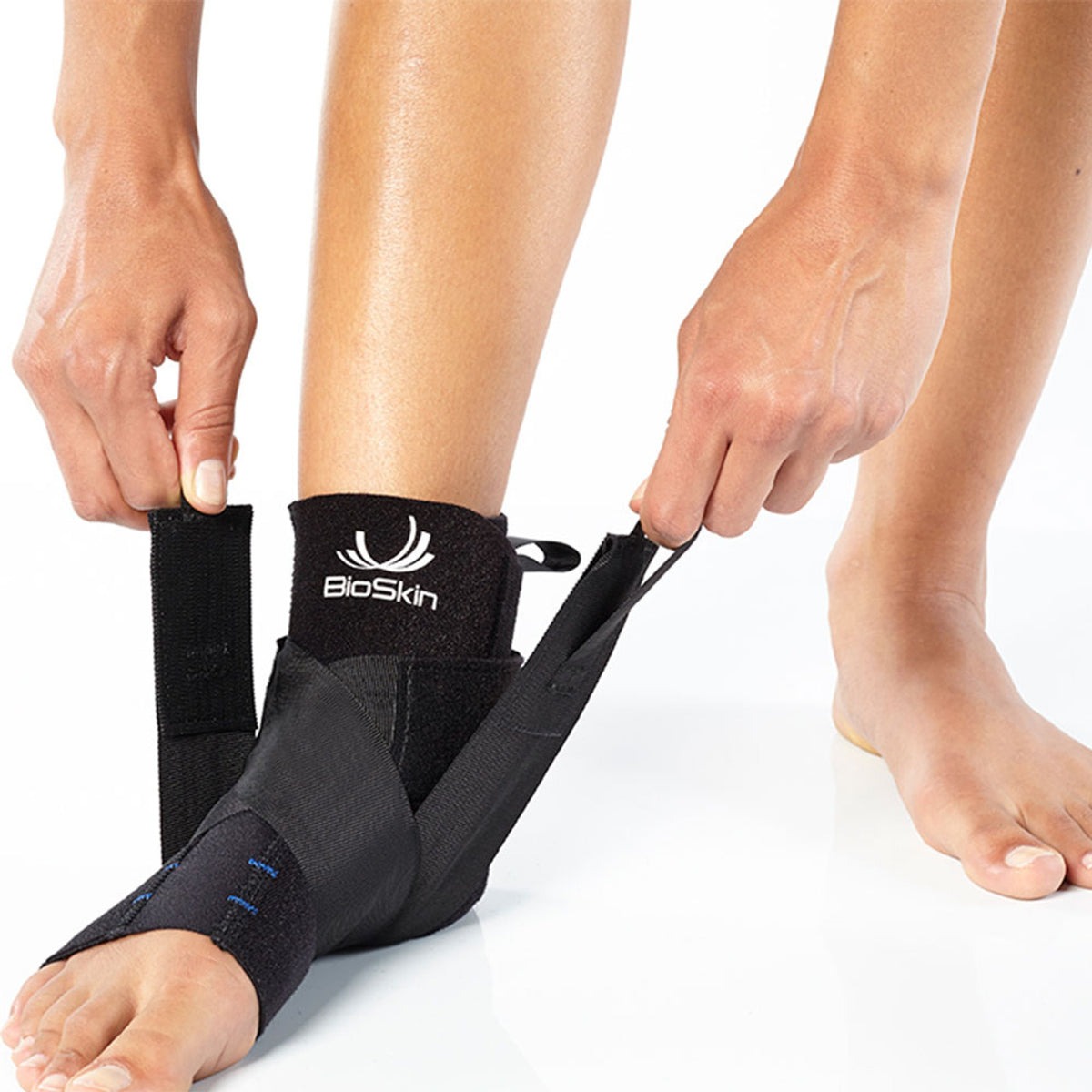BioSkin black pull-on ankle support sleeve with stabilizing straps wrapped around a foot and ankle — view 3